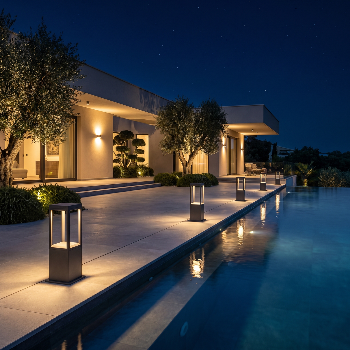 Stanton square bollard lights edging an infinity pool terrace at night