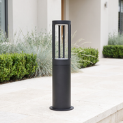 Stanton round LED bollard path light on limestone paving in a modern luxury garden